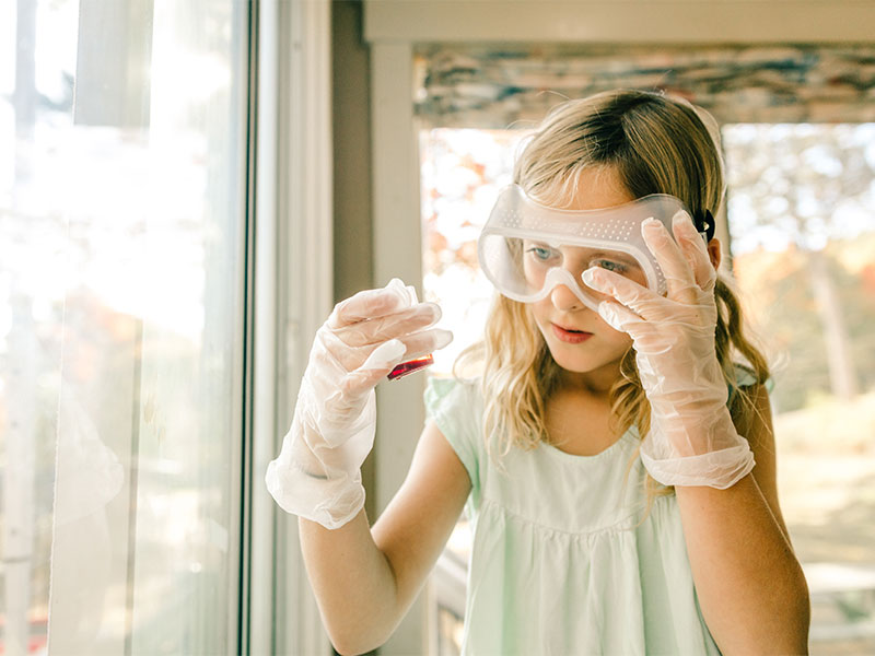 Girl wear goggles and gloves when doing experiment with chemical